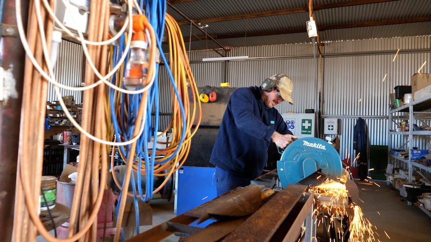 Chapman Valley farmer Brady Green welding in his farm shed with power cords in the foreground.